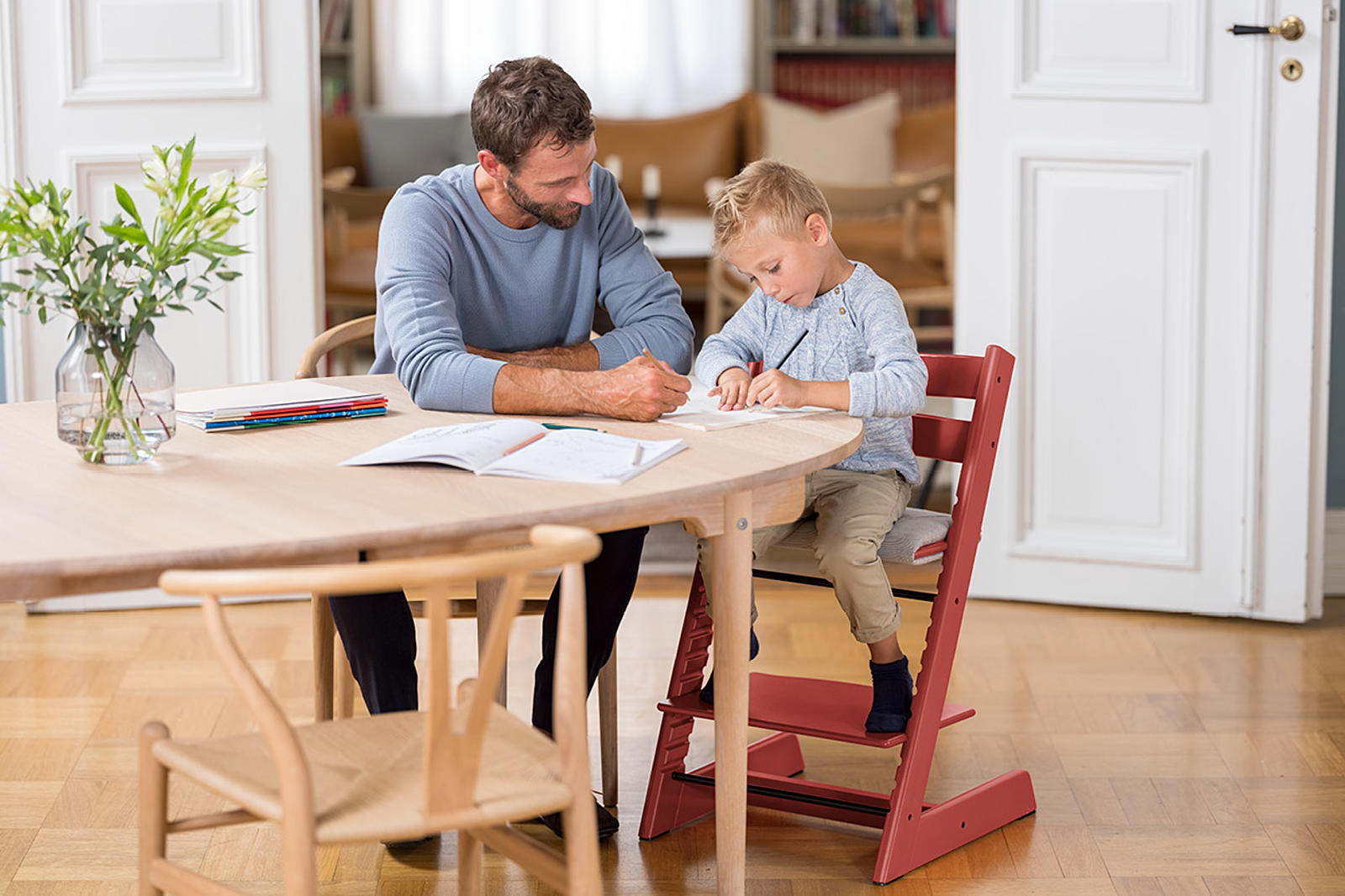 Boy sitting on Tripp Trapp chair and studying with his father